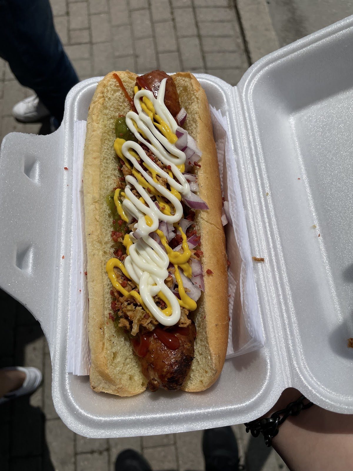 A grilled sausage on a bun with toppings
